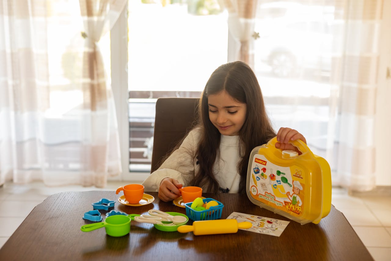 Young girl engaged in imaginative play with a toy kitchen set indoors, cultivating creative skills.